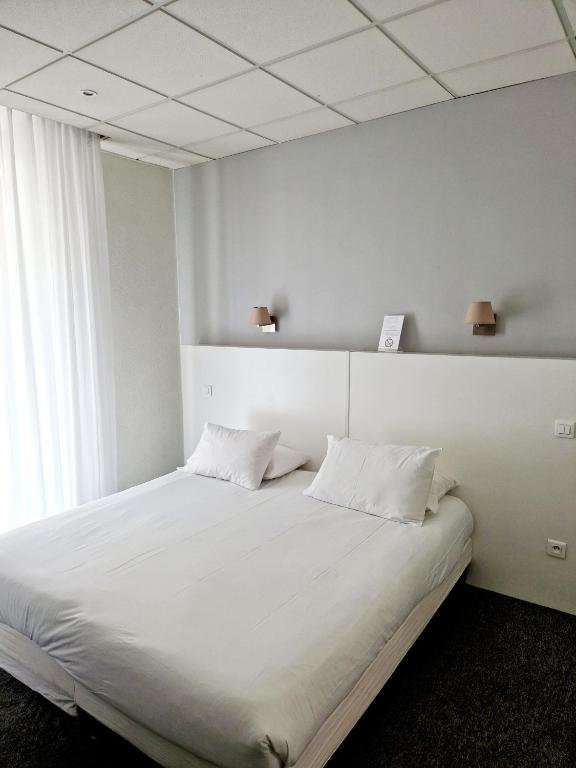 a bedroom with a large white bed with two pillows at Hôtel P.L.M. in Cannes