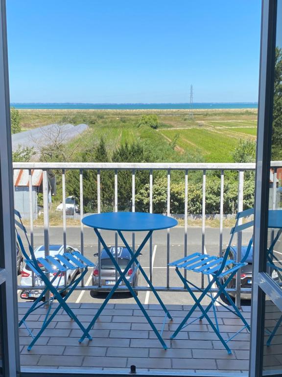 een tafel en stoelen op een balkon met uitzicht op de oceaan bij Appartement vue mer in La Guérinière