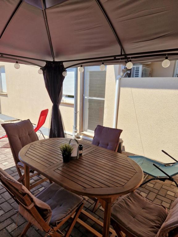 a wooden table with chairs and an umbrella at Apartments Glibo in Cres