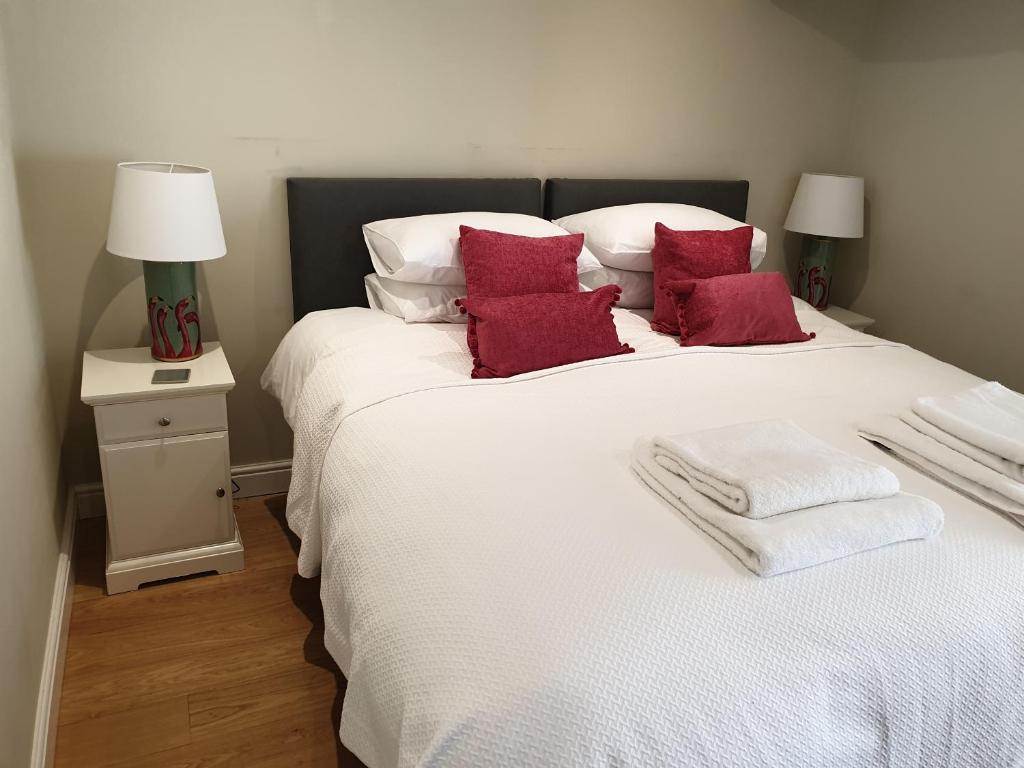 sypialnia z dużym białym łóżkiem z czerwonymi poduszkami w obiekcie Trouble House w mieście Tetbury