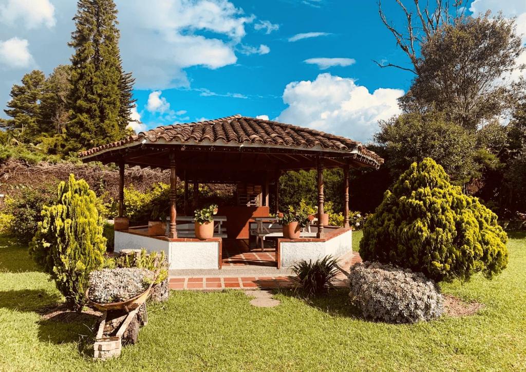 a wooden gazebo in a garden with bushes at Hotel CSI Llanogrande in Rionegro