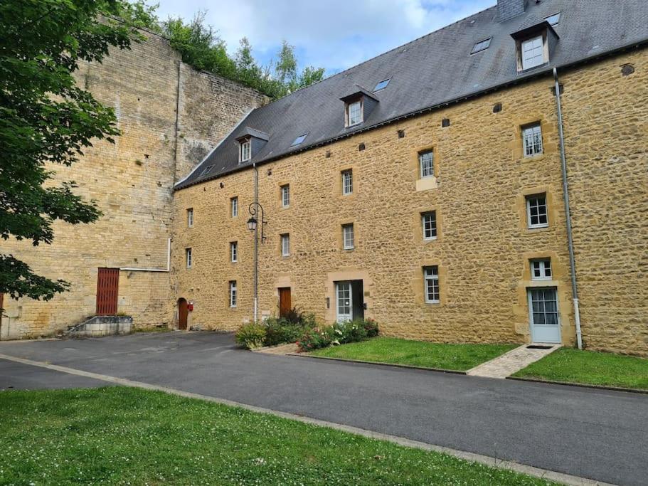 ein großes Backsteingebäude mit einer Straße davor in der Unterkunft Aux remparts du château in Sedan