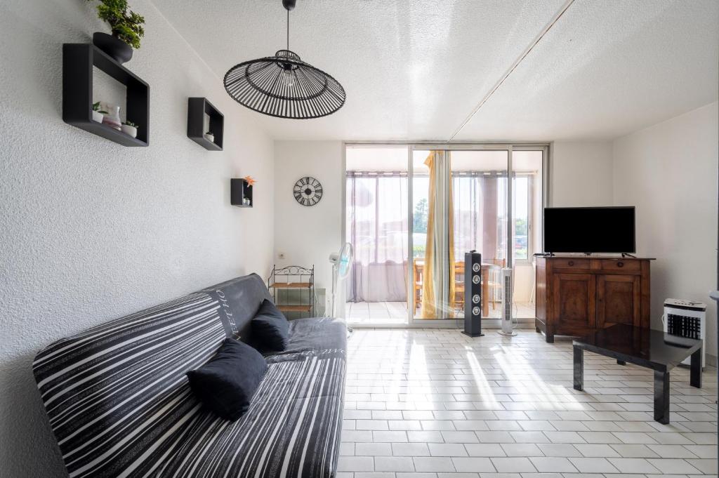 a living room with a couch and a tv at Le Tusco in Cap d'Agde