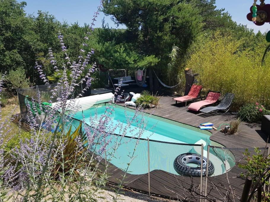 een zwembad in een tuin met stoelen en bloemen bij Villa forest home avec piscine dans les gorges du verdon en Provence in Quinson