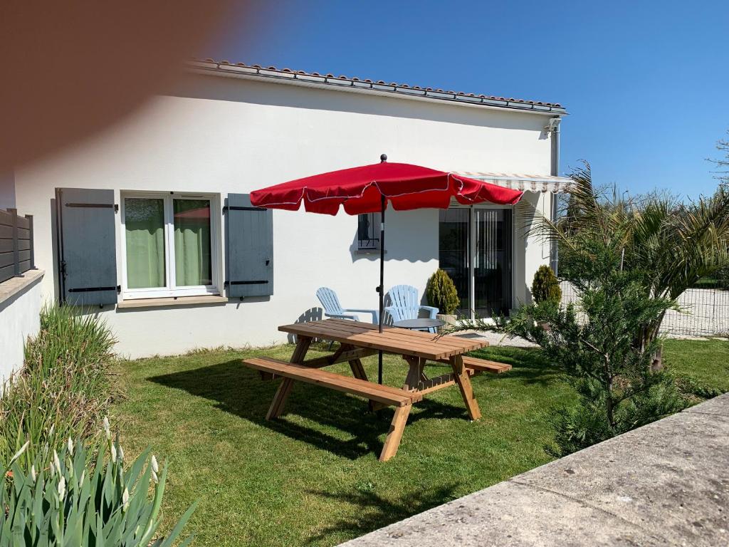 a picnic table with a red umbrella in front of a house at Gîte les Randonneurs in Fontenay-le-Comte