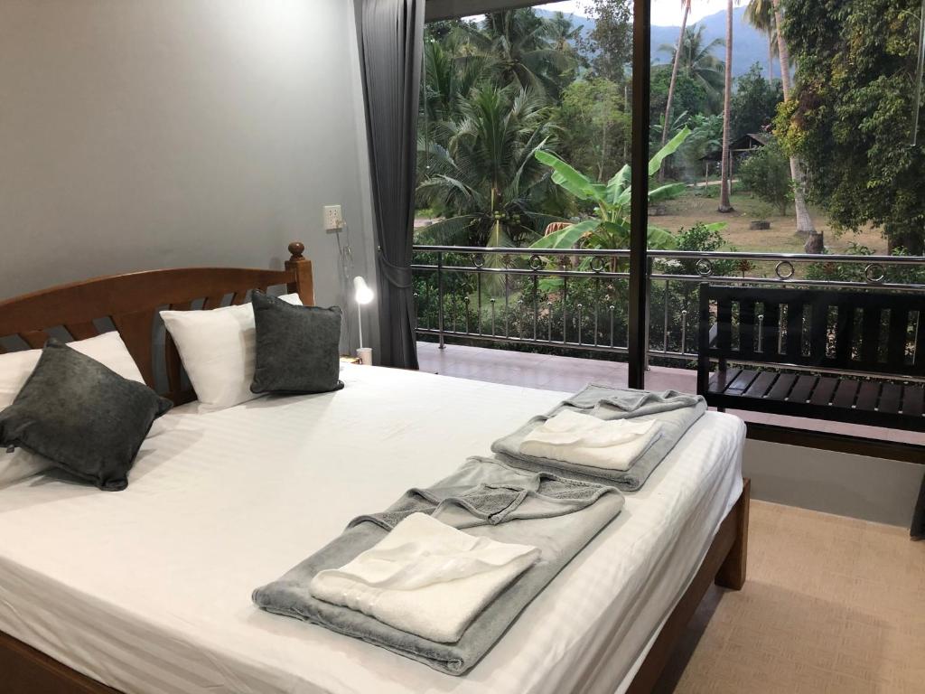 a bedroom with two beds and a large window at Yangyai Garden Lodge in Baan Tai