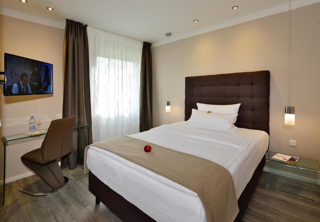 Hotel Haus Kronenthal في راتينغن: غرفة نوم بسرير كبير عليها تفاحة حمراء