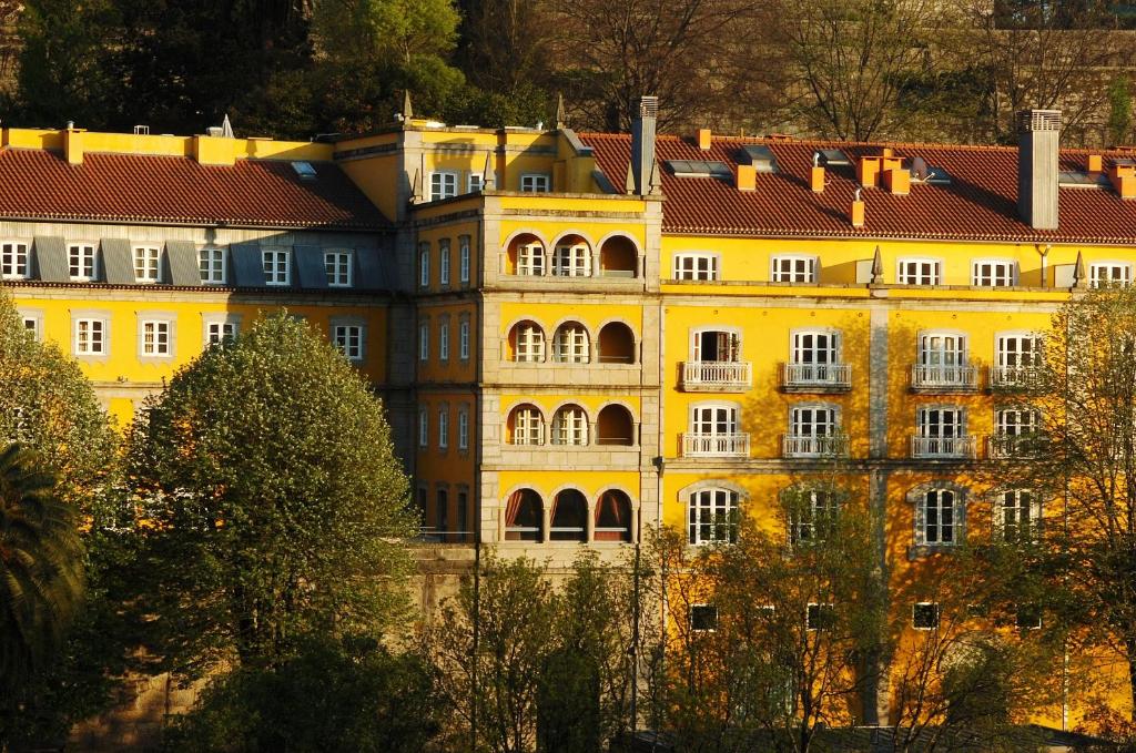 un grand bâtiment jaune avec des arbres devant lui dans l'établissement Hotel Casa da Calçada Relais & Chateaux, à Amarante