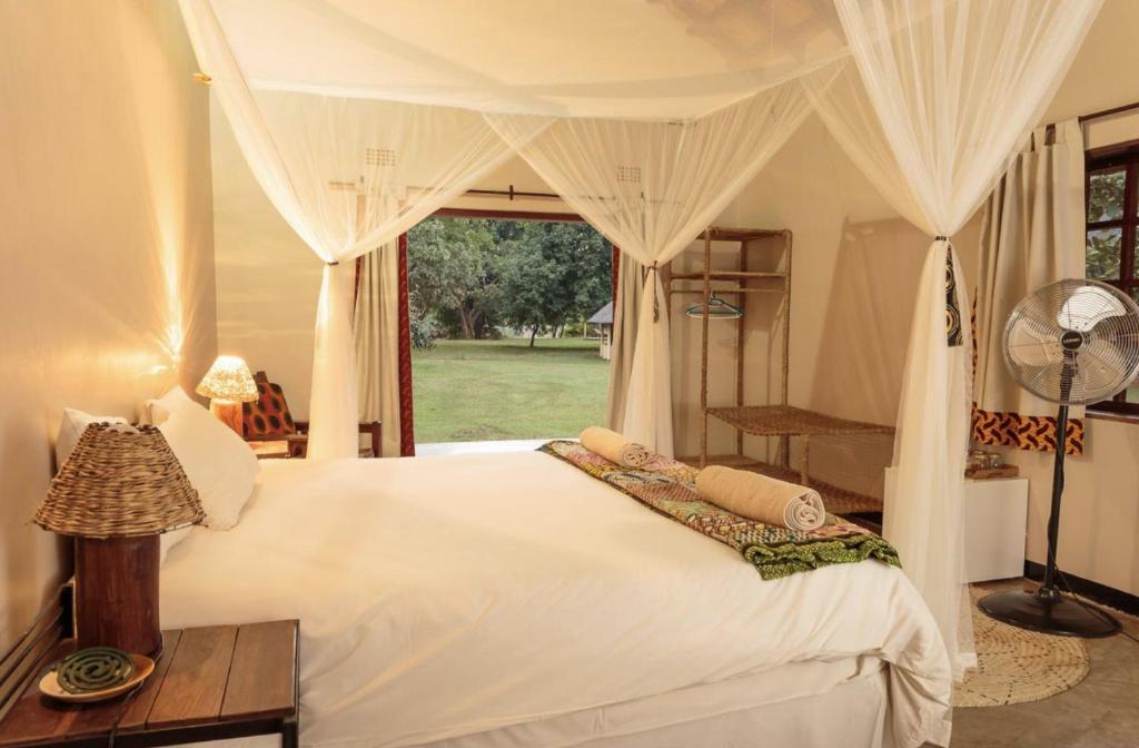 a bedroom with a white bed and a window at Marula Lodge in Mfuwe