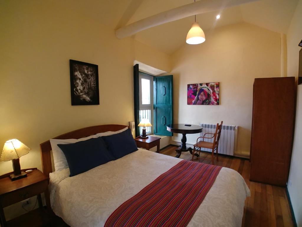 Un dormitorio con una cama y una mesa. en Hostal Corihuasi en Cusco