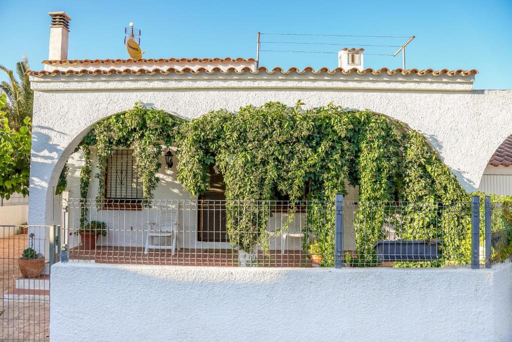 a white building with an arch with ivy on it at Xalet en Riumar,Delta del Ebro in Riumar