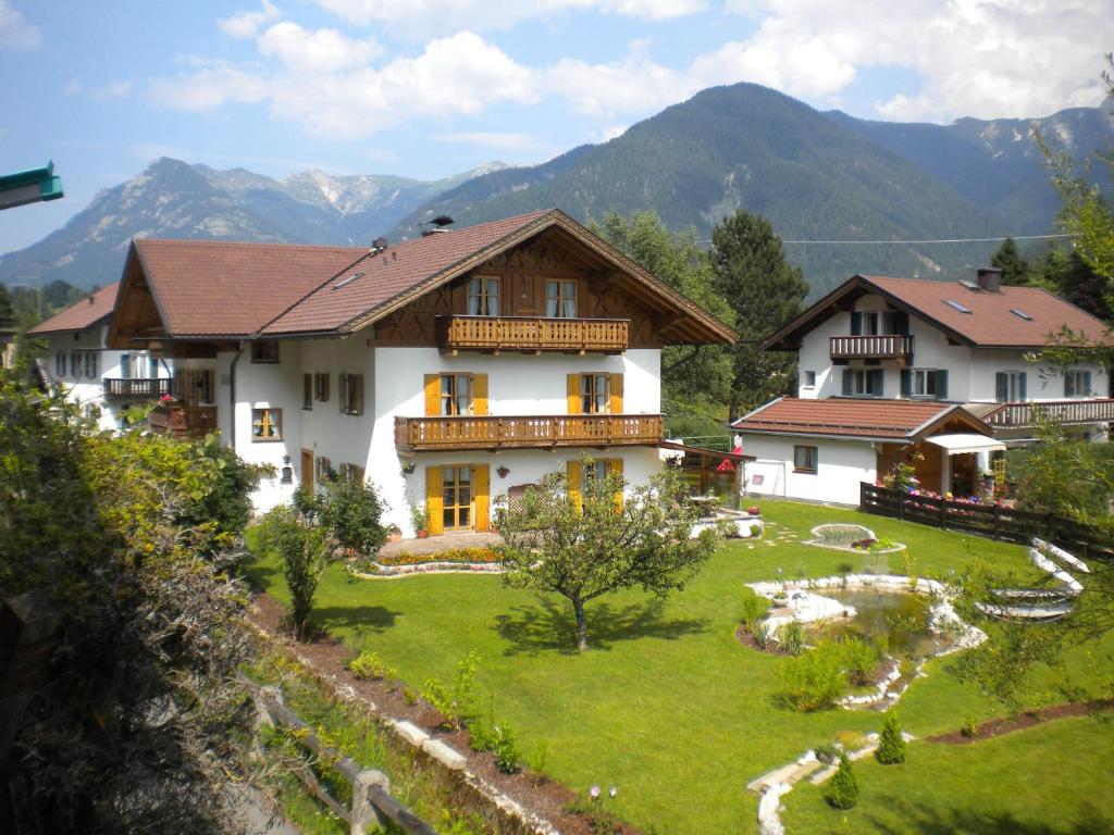 a large house with a yard in front of mountains at Haus Daheim in Mittenwald