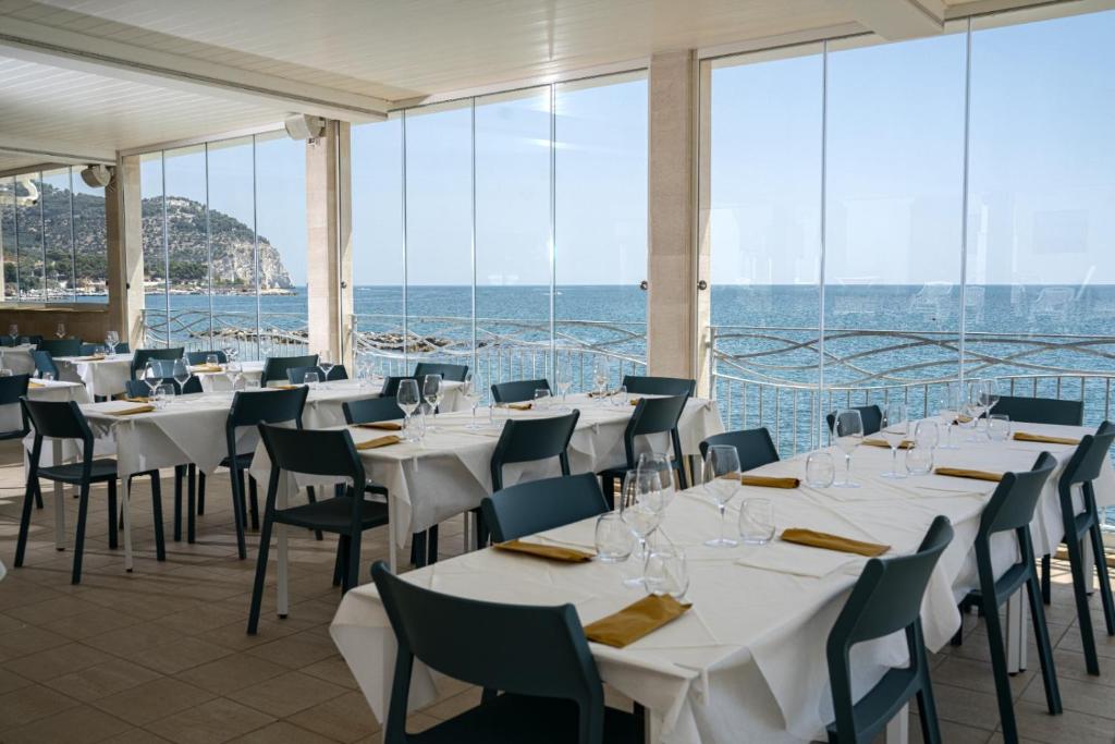 un restaurante con mesas y sillas blancas y el océano en Residence Adriatico, en Mattinata