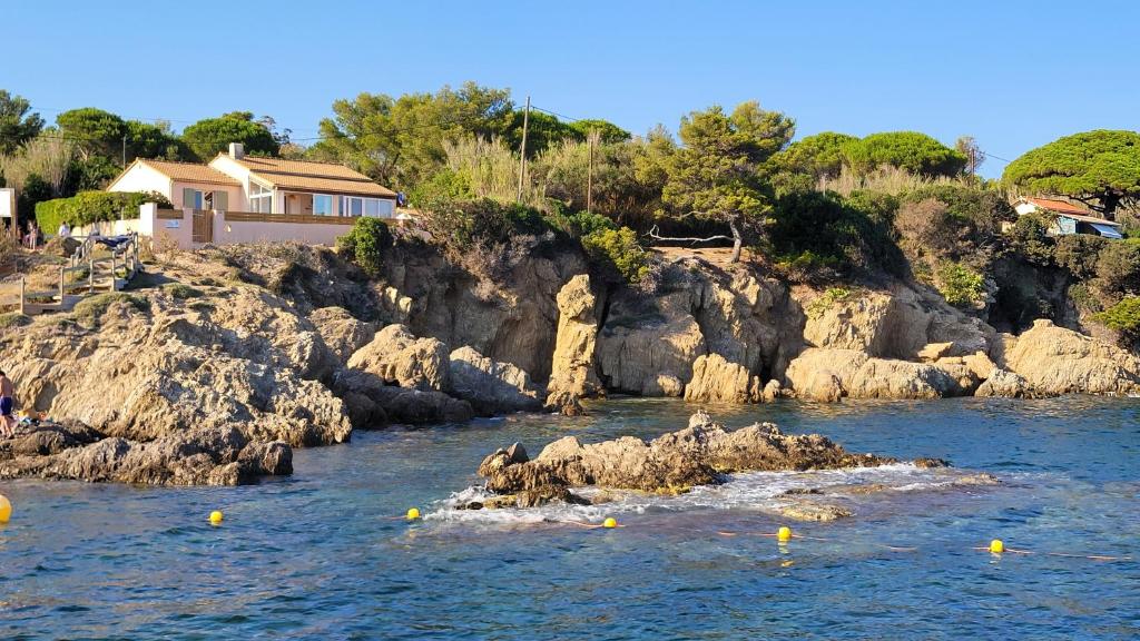 Villa en bord de mer face à l'Ile de Porquerolles في هييريس: نهر فيه صخور في الماء ومنزل