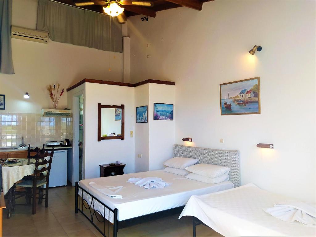 a bedroom with two beds and a kitchen with a counter at Elli Studios & Apartments in Marathokampos