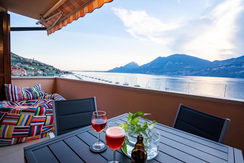 a table with two glasses of wine on a balcony at ORA Beth's House in Brenzone sul Garda