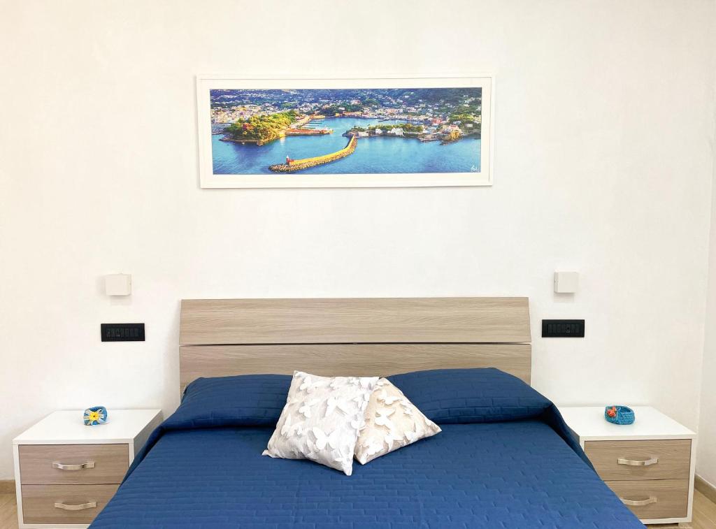 a bedroom with a blue bed and a picture on the wall at Maison Marinella in Ischia