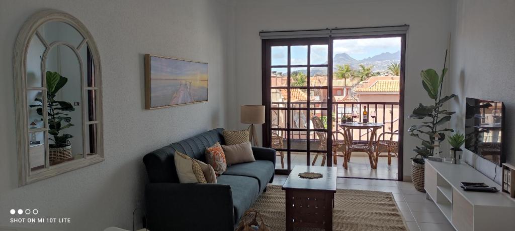 a living room with a blue couch and a balcony at Precioso apartamento con piscina junto al mar in Costa Del Silencio