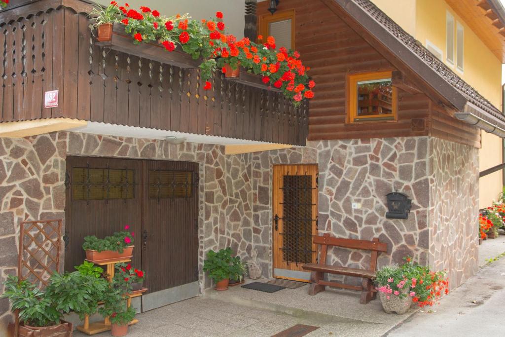 a building with flowers and a bench in front of it at Apartma Erlah in Bohinj