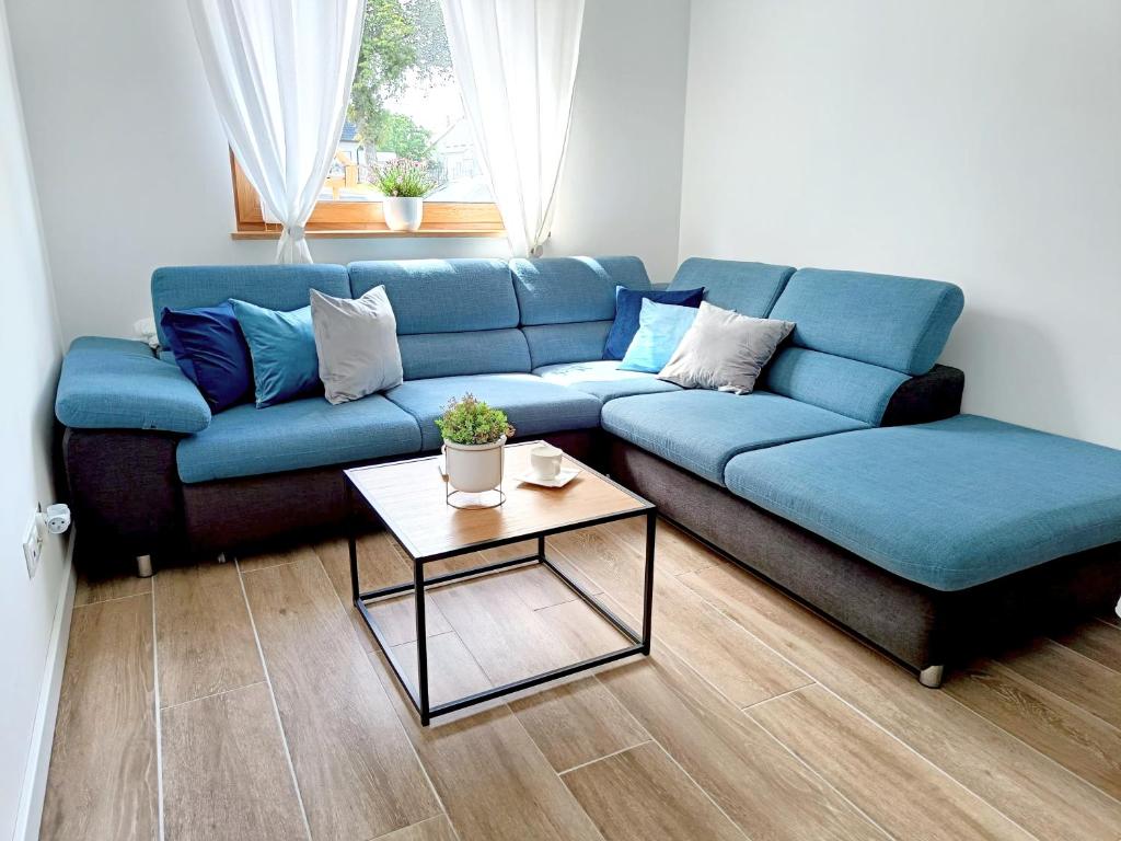 a living room with a blue couch and a table at Kasztanowe zacisze in Połczyno