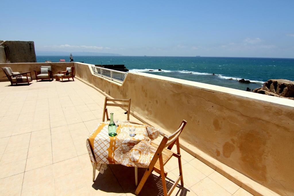 einen Tisch und Stühle auf einem Balkon mit Meerblick in der Unterkunft Nzar Khoury for Hosting in Akkon