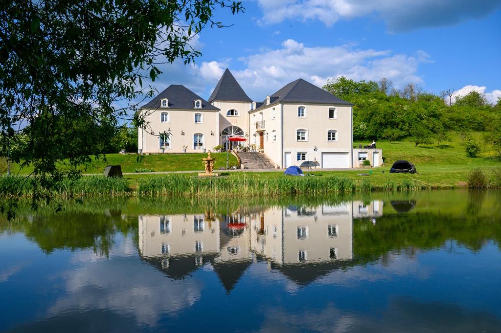 une grande maison blanche avec une réflexion dans l'eau dans l'établissement Domaine de Lardoisière, à Château-Salins