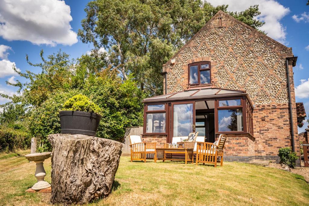 a brick house with a table and chairs in the yard at Morea Cottage - 2 Bed in Horning
