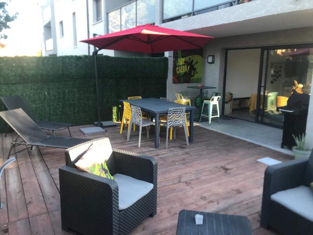 een patio met een tafel en stoelen en een parasol bij Argelès sur mer appartement standing in Argelès-sur-Mer
