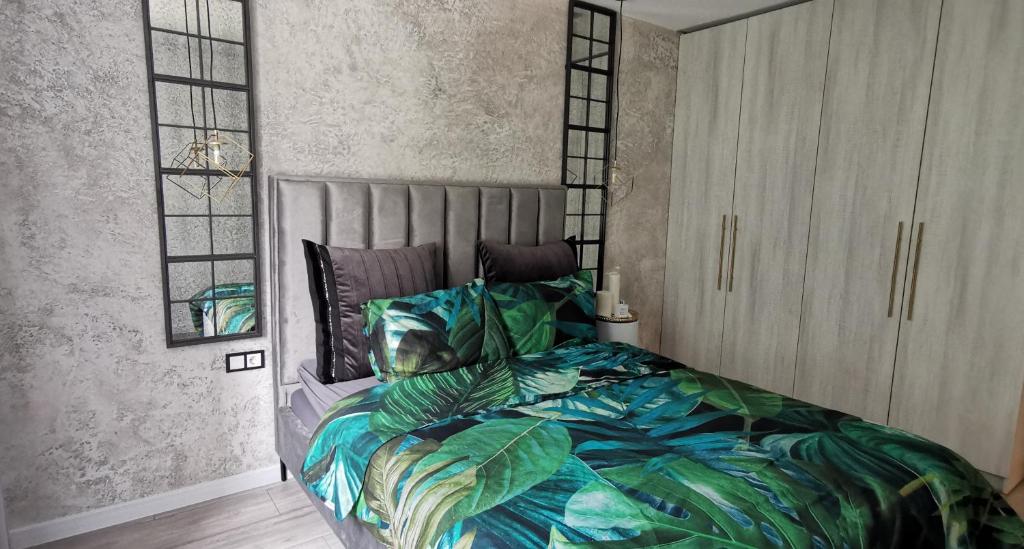 een slaapkamer met een bed met een tropisch thema sprei bij LOCUSDO Apartment No.31 in Mažeikiai