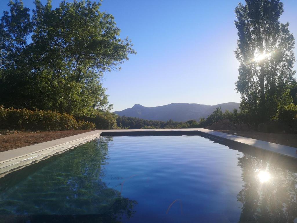 une piscine avec de l'eau bleue et des montagnes en arrière-plan dans l'établissement Studio au calme vue sur garlaban, à Roquevaire