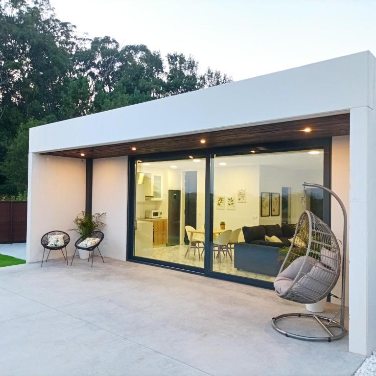 a glass extension of a house with a couch and chairs at Casiña de Cris in Boiro