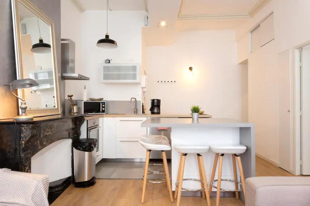 uma cozinha com armários brancos e um balcão com bancos em Magnifique 2 pièces - Plein centre - Tram 1 min em Montpellier