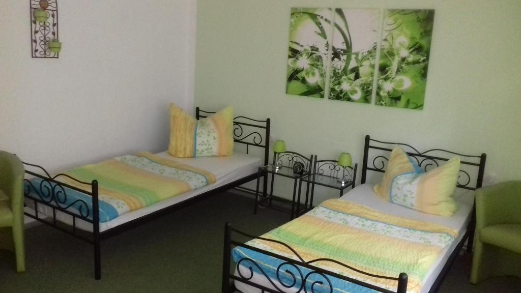 zwei Betten in einem Zimmer mit einem grünen Stuhl in der Unterkunft Ferienhaus Johanna & Ferienwohnung Thum in Weischlitz