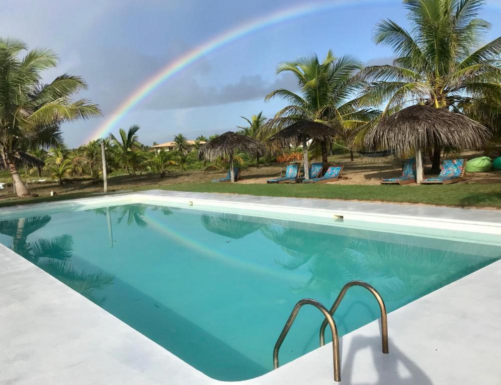 uma grande piscina com um arco-íris ao fundo em Pé na Areia em Conde