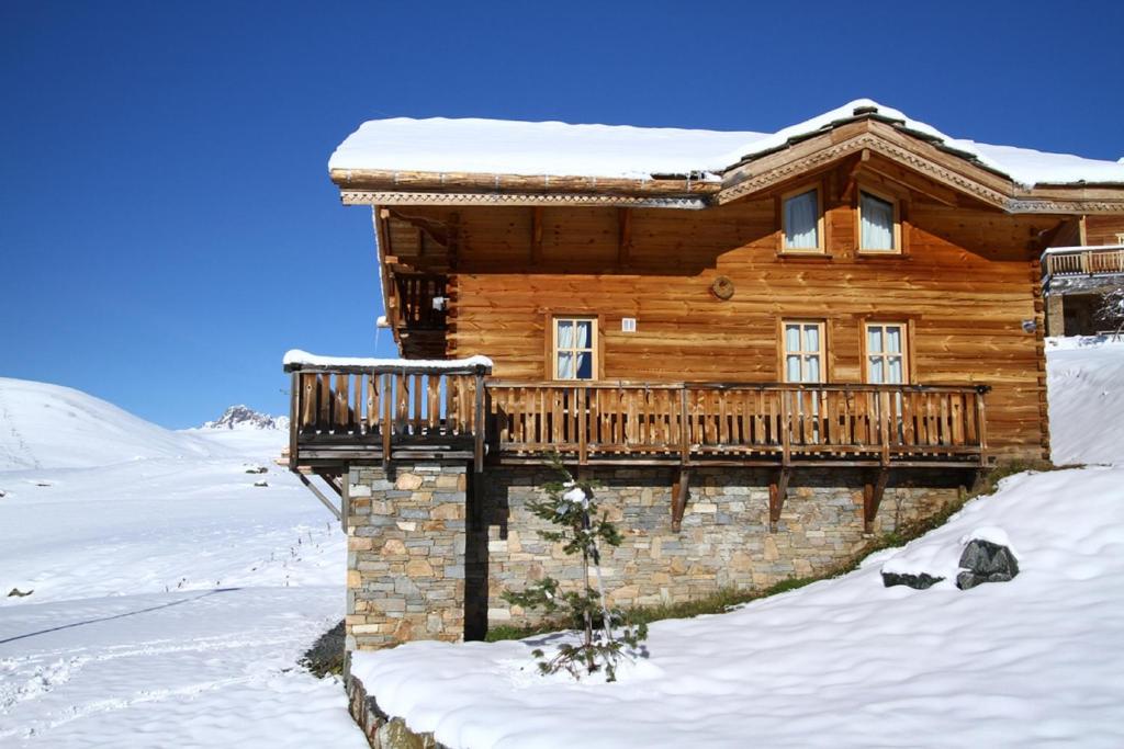 a log cabin in the snow with a deck at Odalys Chalet Melusine in L'Alpe-d'Huez