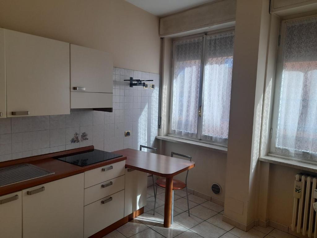 a kitchen with a wooden table and two windows at Giulietta Apartments City Centre Verona in Verona