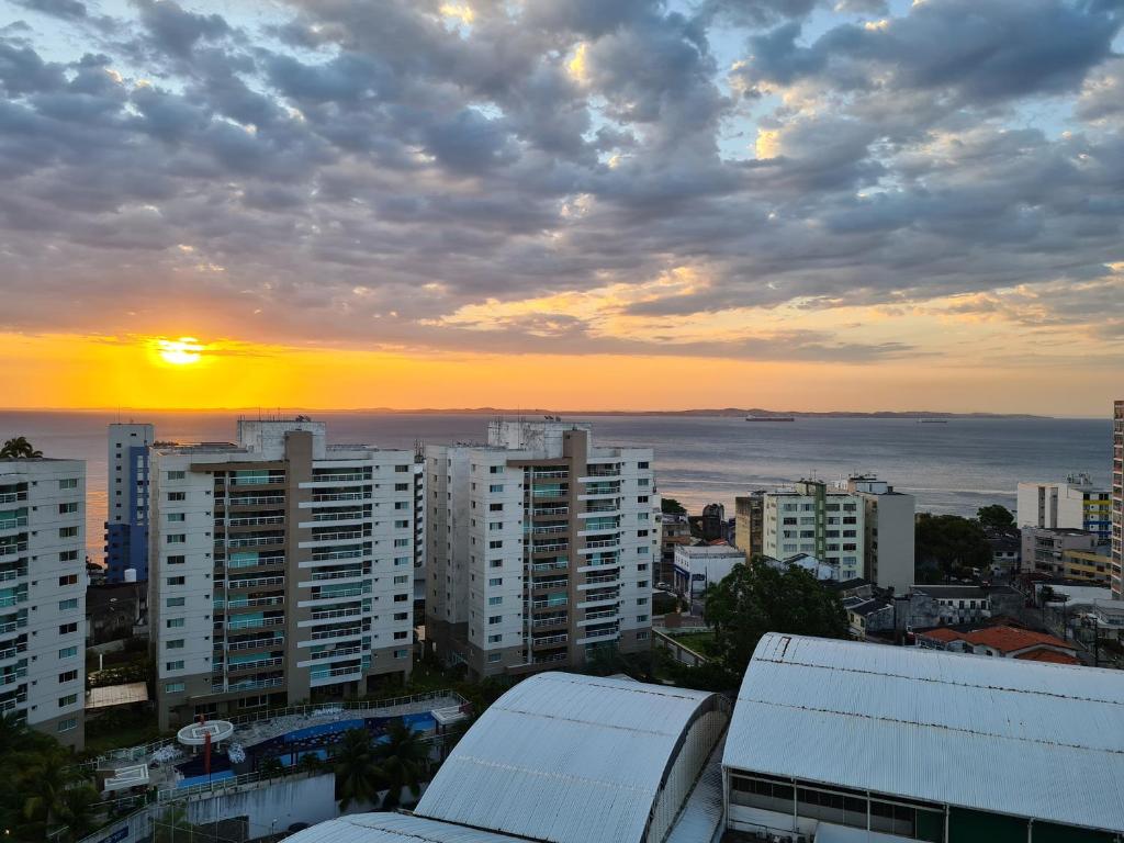 una puesta de sol sobre una ciudad con edificios y el océano en Vista Mar - Conforto e Tranquilidade, en Salvador
