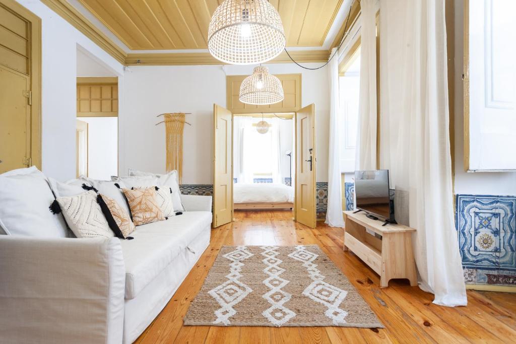 een woonkamer met een witte bank en een tv bij Yellow Tiles in City Center in Lissabon