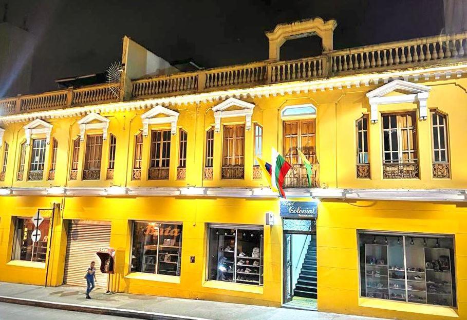 un edificio amarillo con una persona caminando delante de él en Hotel Colonial Manizales, en Manizales