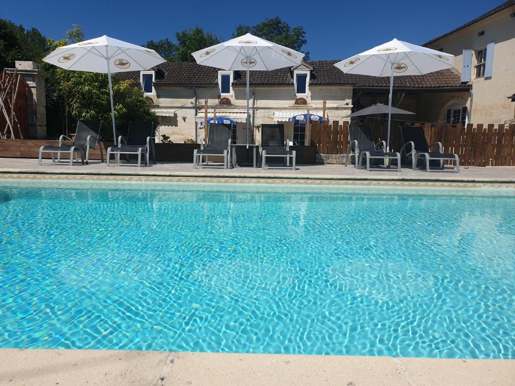 una piscina con sillas y sombrillas junto a en La Charrue gite complex en Monsec