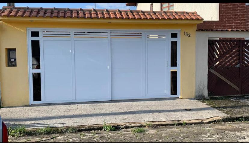Un par de puertas de garaje blancas en una casa. en Casa de praia aconchegante próxima ao centro, en Mongaguá