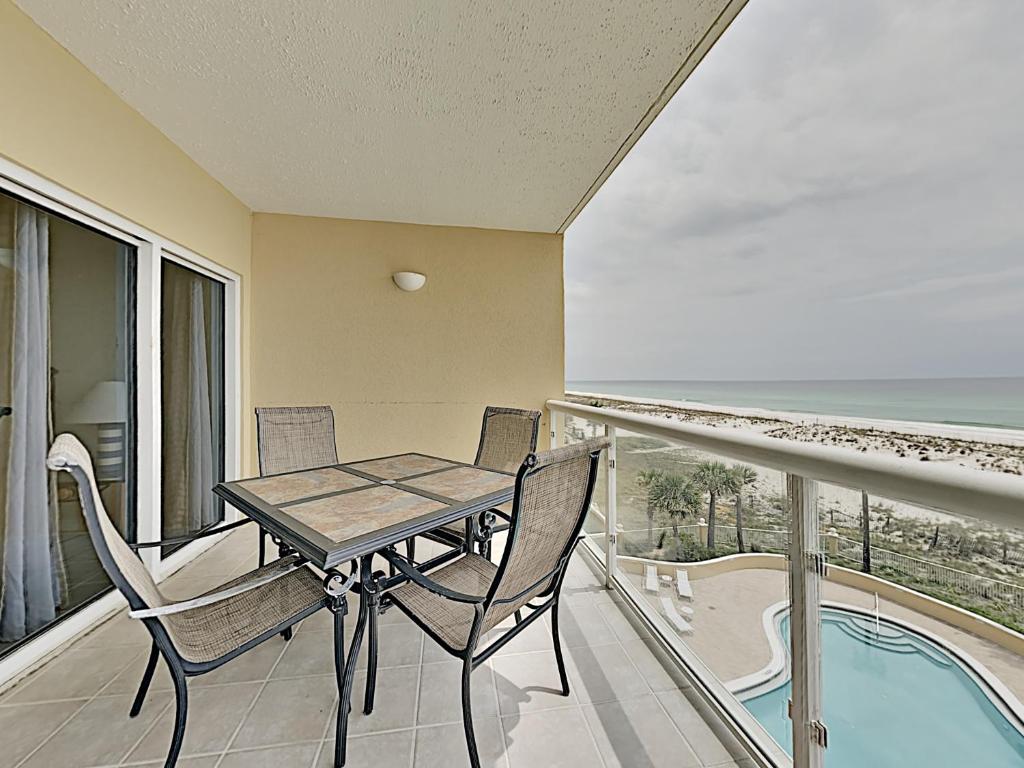 Un balcón con mesa y sillas y una piscina. en Emerald Isle #304, en Pensacola Beach