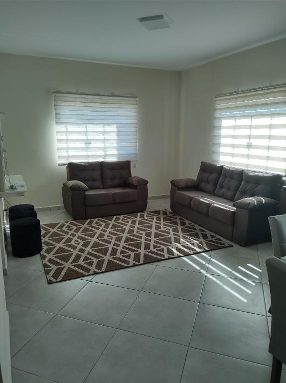 Una sala de estar con dos sofás y una alfombra. en Apartamento mobiliado com vista exclusiva da Serra, en Cruzeiro
