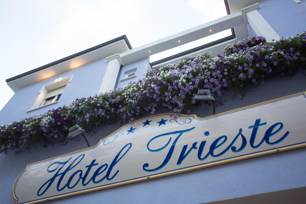 un cartello hotel con fiori sul lato di un edificio di Hotel Trieste a Cesenatico