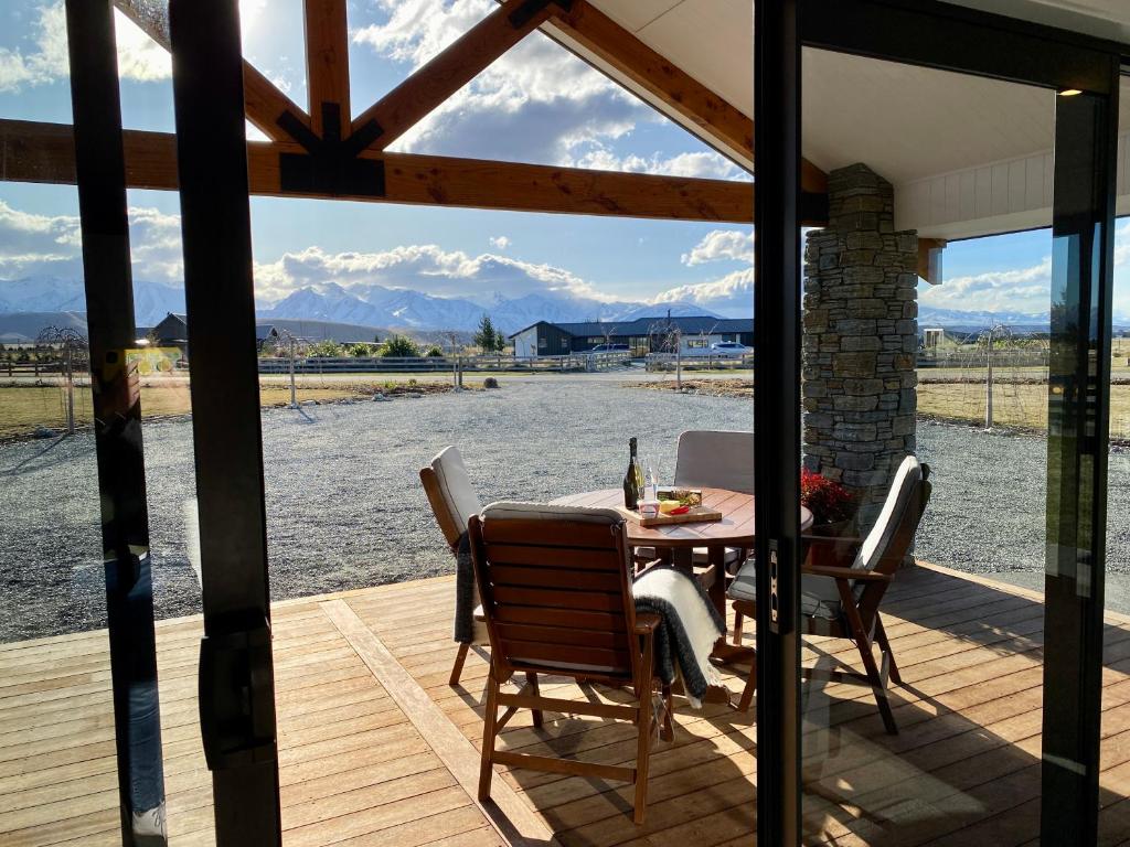 a table and chairs on a deck with a view of the water at Uninterrupted Mountain Views in Twizel