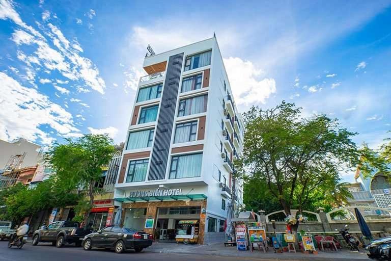a tall white building on a city street with cars at Hương Biển Hotel in Quy Nhon