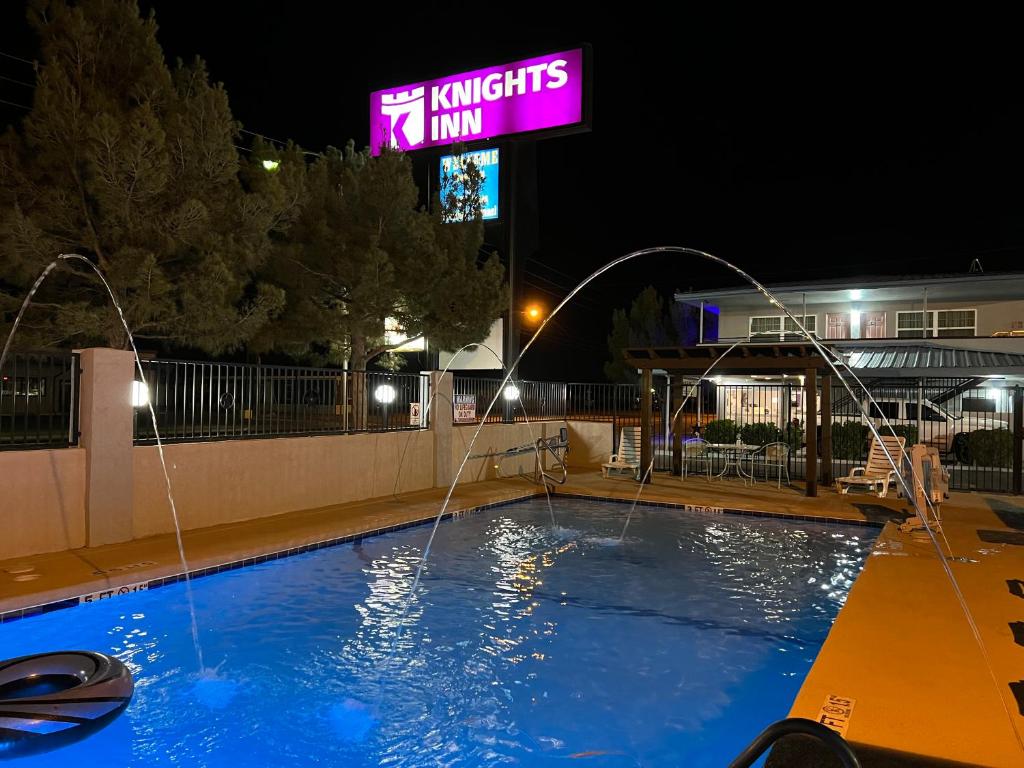 - une piscine la nuit avec un panneau indiquant l'auberge des chevaliers dans l'établissement Knights Inn & Suites by Sonesta Pecos, à Pecos