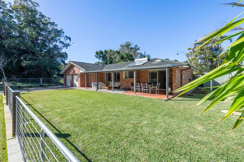 a brick house with a lawn in front of it at Rainforest Retreat in Iluka