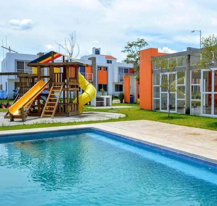 einen Spielplatz mit Rutsche neben einem Pool in der Unterkunft hermosa casa en coto privado especial para ti y tu familia in Tepic