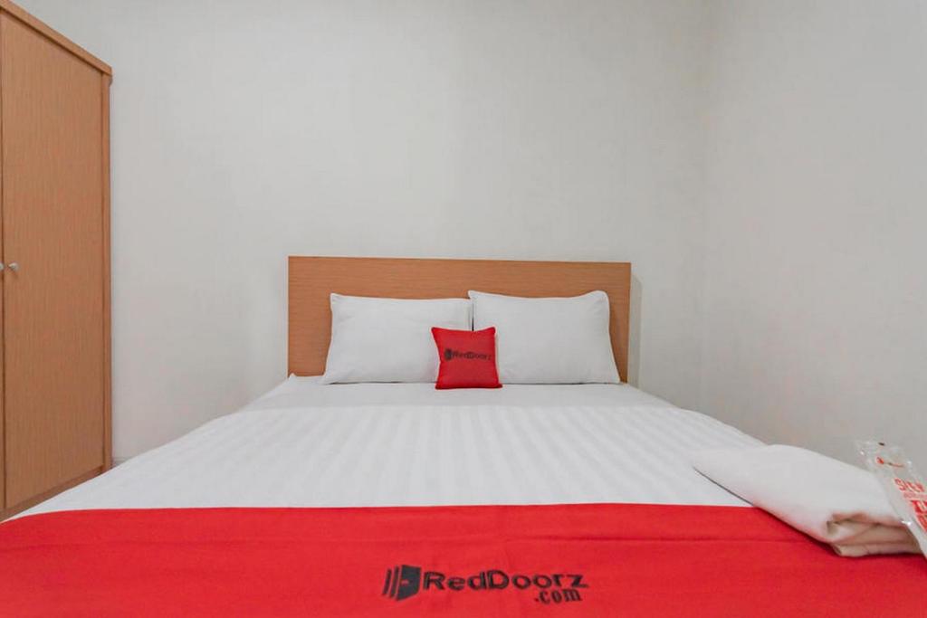 a bedroom with a bed with a red pillow on it at RedDoorz Syariah near Karawang Central Plaza in Karawang
